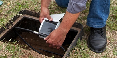 Hands wrapping mastic electrical tape around underground cable
