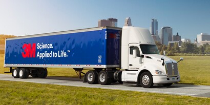 blue graphic film with a 3M logo wrapped on the body of a commercial fleet truck driving down a city road
