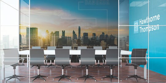 An office conference room has graphic wraps with a cityscape on one wall, and a company name and logo on another wall.
