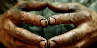 ภาพระยะใกล้ของมือที่เปรอะเปื้อนโดยมีการกดปลายนิ้วเข้าหากัน
