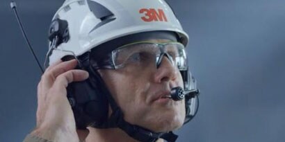 มุมมองด้านข้างของคนงานสวมแว่น 3M หมวกแข็ง และอุปกรณ์สื่อสาร
