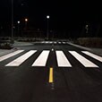 Low-angle shot of white painted crosswalk across road.