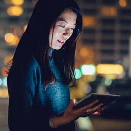 Dark-haired woman looking at 5G optimized tablet