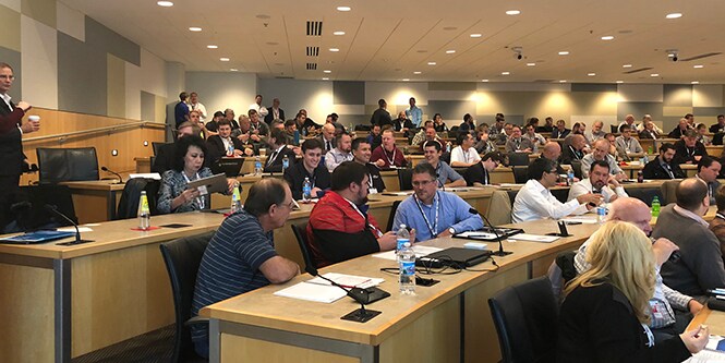 image of individuals sitting at desks, attending an event
