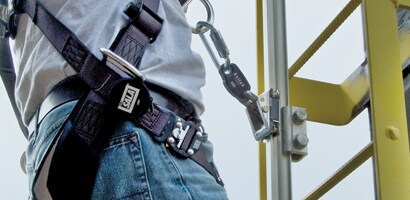 Worker climbing tower ladder connected to rigid rail ladder safety system
