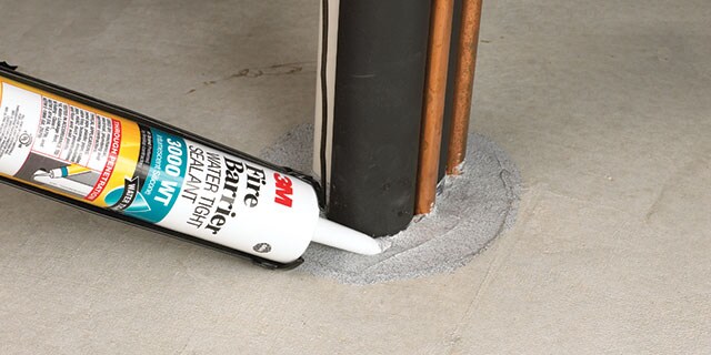 Worker applying a 3M firestop product to a through-penetration

