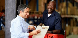 Image of a worker with clipboard consulting with a colleague operating a machine
