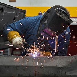 Sparks fly as technician welds metal substrates together in a factory