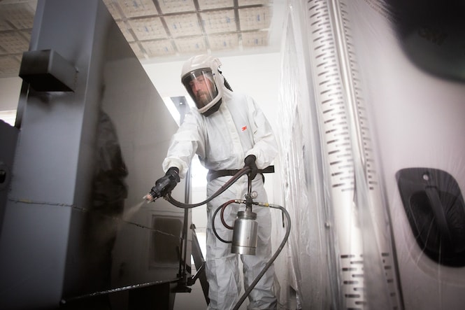 image of person using a spray gun in an industrial setting
