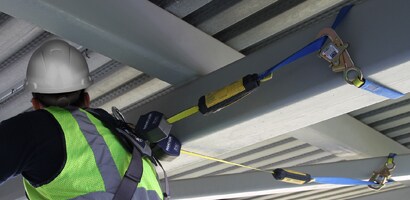 Worker among beams connected by pair of self-retracting lanyards
