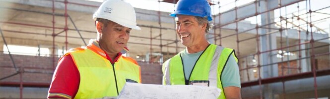 Image of two construction workers discussing a set of plans on a job site