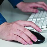 Man in warehouse on laptop completing an online medical evaluation