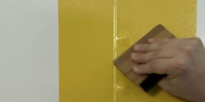 A hand smooths a yellow graphic wrap.
