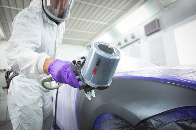 image of person using spray gun in a collision repair setting
