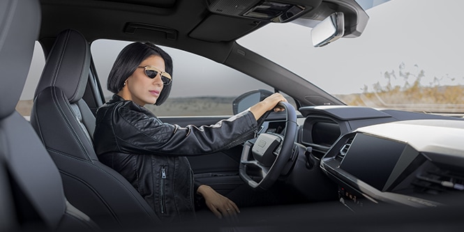 ผู้หญิงสวมแว่นกันแดดและแจ็คเก็ตหนังขับรถที่ติดฟิล์มกรองแสงรถยนต์