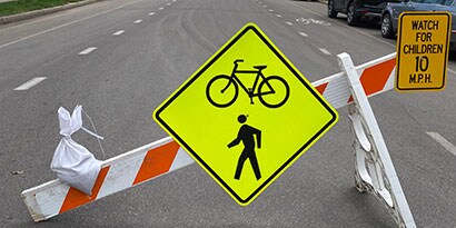 Temporary traffic signs on a barrier indicate that bicycles and pedestrians are allowed and to watch for children.
