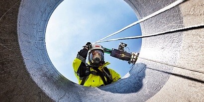 Person wearing 3M Supplied Air System, looking down into a confined space
