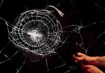 hand holding a pen to a broken glass