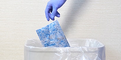 gloved health care cleaning professional disposing of a 3M disposable mop pad
