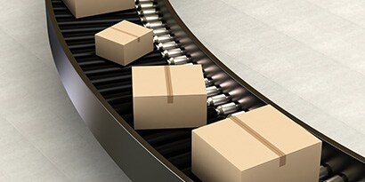 Image of sealed cartons moving along a curved conveyor belt
