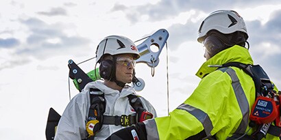 Two workers in protective gear preapring to enter a confined space using a davit.
